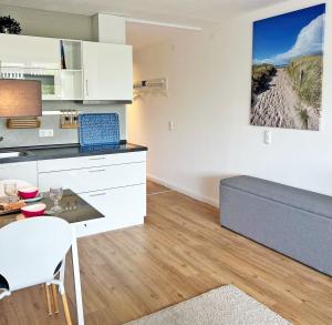 a kitchen with white cabinets and a table and a couch at Driftberg 1 Whg 18 in Grömitz