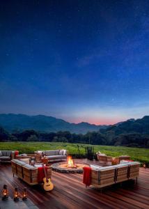 - une terrasse avec des canapés et un foyer extérieur la nuit dans l'établissement One&Only Nyungwe House, à Rwumba