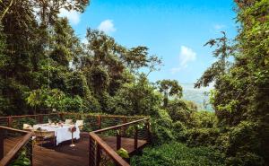 - une table à manger sur une terrasse dans la forêt dans l'établissement One&Only Nyungwe House, à Rwumba