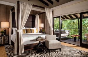 una camera con letto e sedia e un patio di One&Only Nyungwe House a Rwumba