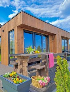 a wooden house with a bench and flowers on the deck at Domki Letniskowe Rewa in Rewa