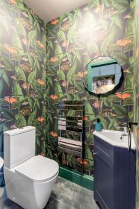 a bathroom with a toilet and a tropical wallpaper at 4-br Free Parking Fast Wi-fi Workstation in Norwich