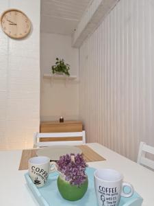 une table avec deux tasses et un bol de fleurs violettes dans l'établissement Chez Nous, à Cherbourg en Cotentin