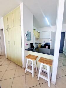 a kitchen with a counter and two stools in a room at OCEAN WHISPER II - Power back up, Sea facing, Umdloti in Umdloti