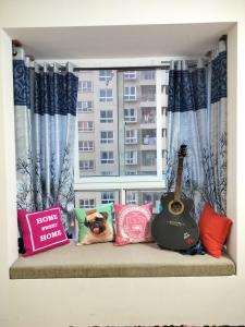 a couch with pillows and a guitar in a window at SOLACE Premium 3BHK Apartment Manyata Tech Park and Mall of Asia in Bangalore