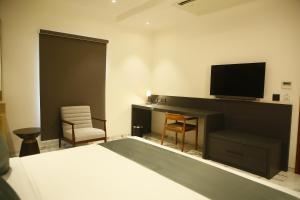 a bedroom with a bed and a tv and a desk at Hotel Golden Tower At Delhi Airport in New Delhi