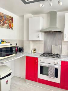 uma cozinha com armários vermelhos e um fogão em Westfield Gardens Apartment - 3 bedrooms em Goodmayes