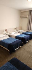 three beds in a room with blue sheets at Ünver Hotel in Adana