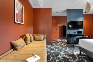 a living room with a couch and a tv at LE RITUEL HOTEL & SPA in Honfleur