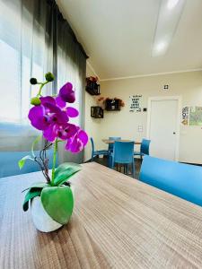 a vase with purple flowers sitting on a table at Hotel Bed & Bike in Cesena