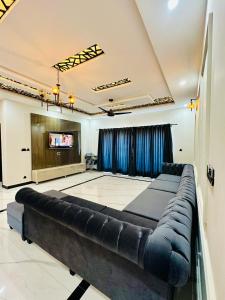 Luxurious kashmir house near Islamabad airport في Dhok Sandemār: أريكة كبيرة في غرفة مع تلفزيون بشاشة مسطحة
