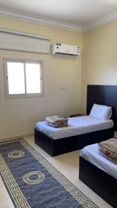 a bedroom with two beds and a window and a rug at شقق العاصفه4 in Khamis Mushayt