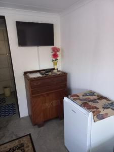 a room with a television and a dresser and a refrigerator at Eloff's Guest House in Polokwane