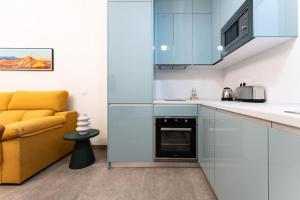 a kitchen with blue cabinets and a yellow couch at Apartamento para 4 personas en centro historico de Almeria in Almería