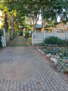 a fence with a brick walkway next to a garden at Eloff's Guest House in Polokwane