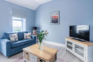 Sala de estar azul con sofá azul y TV en Harbour Heights - 2 Bed Apartment - Milford Haven en Milford Haven