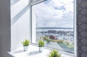 an open window with potted plants on a window sill at Beach Haven Hideout - 2 Bedroom - Milford Haven in Milford Haven