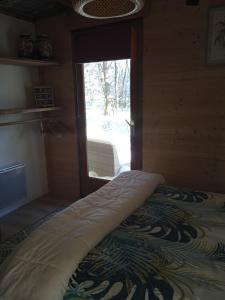 uma cama num quarto com uma porta de vidro deslizante em Chalet coccinelle Domaine de la Mamounette em Champclause