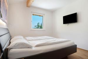 Posto letto in camera con TV a parete di Bacchushof Apartment Sauvignon a Termeno