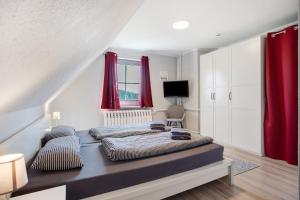 a bedroom with a large bed with red curtains at Rügenferienhaus eg und og in Schaprode