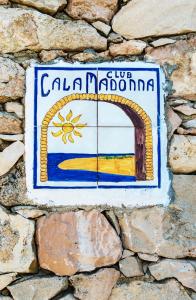 un panneau indiquant une ville sur un mur de pierre dans l'établissement Calamadonna Club Hotel, à Lampedusa