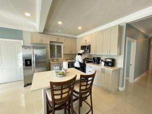 a kitchen with a table and a person in a kitchen at Villa in Drax Hall, Private Beach, Chef Incl in Saint Annʼs Bay