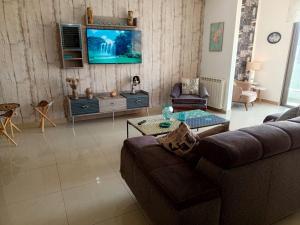 a living room with a couch and a tv on a wall at New apartment in Tilal Fanar resort pool Tennis in Beit Meri