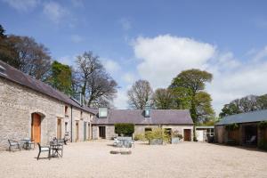 um edifício de tijolos com cadeiras e mesas num pátio em June Blake's Garden em Blessington