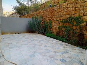 a patio with a stone wall and a tile floor at New apartment in Tilal Fanar resort pool Tennis in Beit Meri