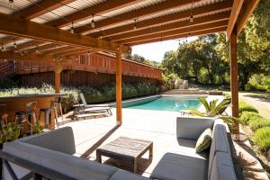 une terrasse avec une piscine et une pergola en bois dans l'établissement Serene Vineyard Chateau with Pool, Hot Tub, BBQ, à Carmel Valley