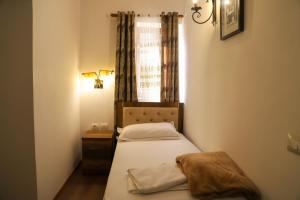 een kleine slaapkamer met een bed en een raam bij DD Villa in Berat