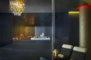 a room with a fireplace with two chairs and a chandelier at Aminess Vival Maestral Hotel in Novigrad Istria