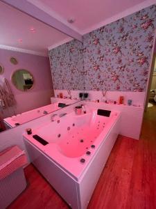 a pink bath tub in a room with floral wallpaper at La bulle romantique in Calais