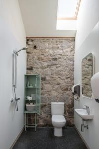 a bathroom with a white toilet and a stone wall at June Blake's Garden in Blessington