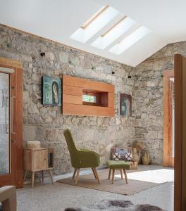 a living room with a green chair and a stone wall at June Blake's Garden in Blessington