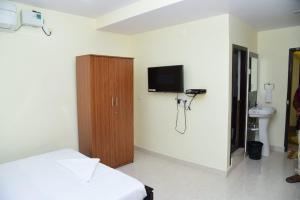 Habitación con cama y TV en la pared. en ARUNA GRAND en Visakhapatnam