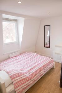 1 dormitorio con 1 cama con edredón a rayas y ventana en Lille Moulin, duplex lumineux 4P en Lille