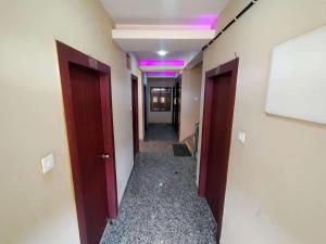 Goroomgo Hotel Casa Di William Khajuraho في خاجوراهو: ممر من ممر مع أبواب وأضواء أرجوانية