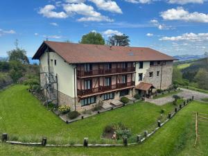 una casa grande en una colina con un campo verde en Hotel-Apartamento Rural Atxurra, en Bermeo