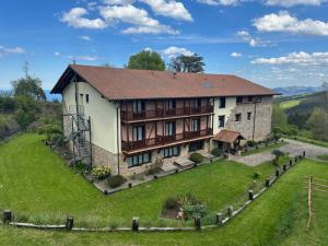 a large house on a hill with a green field at Hotel-Apartamento Rural Atxurra in Bermeo