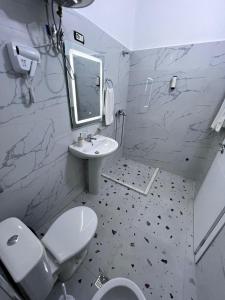 a white bathroom with a toilet and a sink at Prime Luxury Apartments in Lushnjë