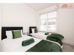 ダーリントンにある3BR House in Darlington - Near Airport FREE Parkingのベッドルーム1室(ベッド2台、緑のシーツ、窓付)