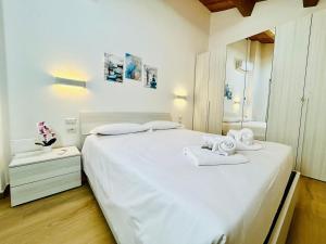 una camera da letto con un grande letto bianco con asciugamani di SMART SUITES FORLI' a Forlì