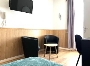 Cette chambre dispose de 2 chaises, d'une table et d'une télévision. dans l'établissement Hôtel de la Gare, à Cherbourg en Cotentin