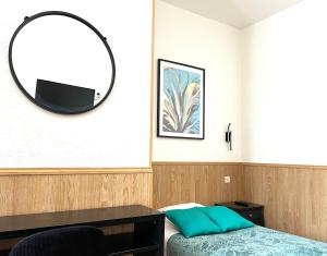 シェルブール・アン・コタンタンにあるオテル ドゥ ラ ガールの鏡、ベッド、デスクが備わるベッドルーム1室が備わります。