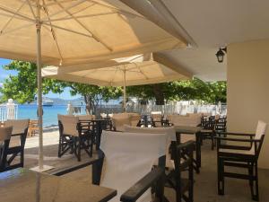un restaurante con mesas, sillas y sombrillas en Akrogiali, en Agiokampos