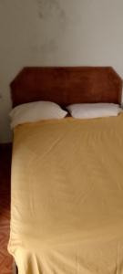 un letto con 2 cuscini e una testiera in legno di pablo guess house a Cap-Haïtien