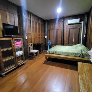 1 dormitorio con 1 cama, TV y paredes de madera en ณ ลำพญา, 