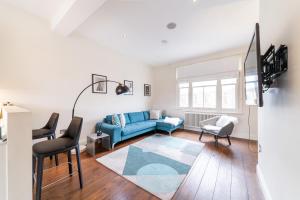 ein Wohnzimmer mit einem blauen Sofa und Stühlen in der Unterkunft Mrs K Stunning 3 bedrooms apartment Chelsea in London