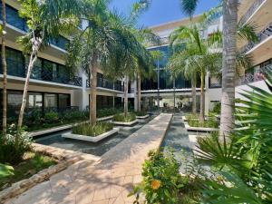 an empty courtyard with palm trees in front of a building at Unwind | Private Balcony & Rooftop Pools | Casago in Tulum